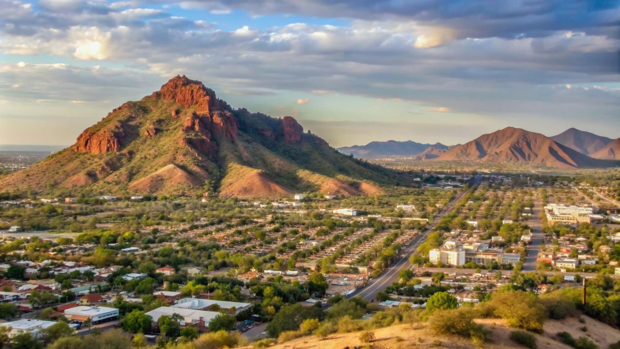 Aerial view of a Phoenix-area neighborhood below a red rock butte at sunset