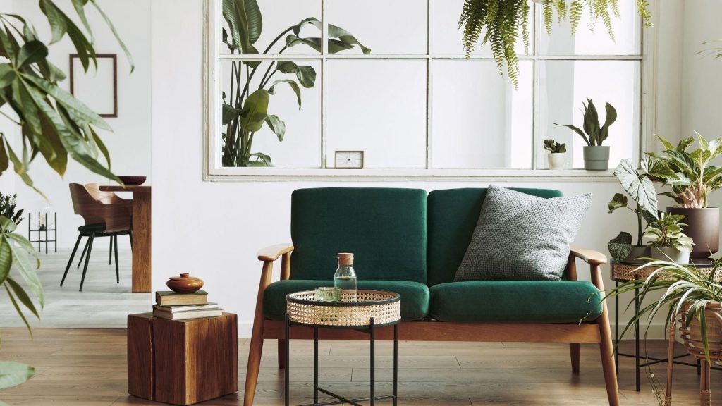 Staged living room with a green velvet sofa and houseplants